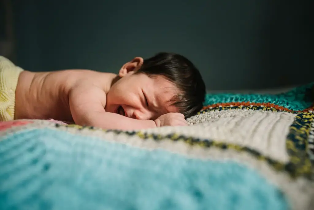 An image of a Crying baby on knitted blanket.