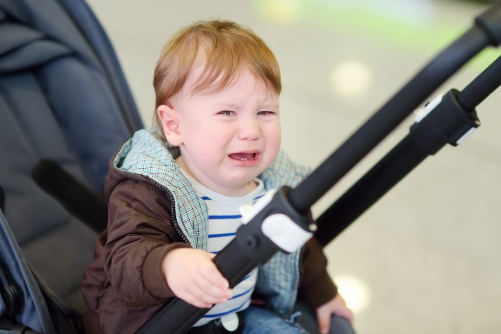 An image of a Screaming little baby boy sitting in stroller.