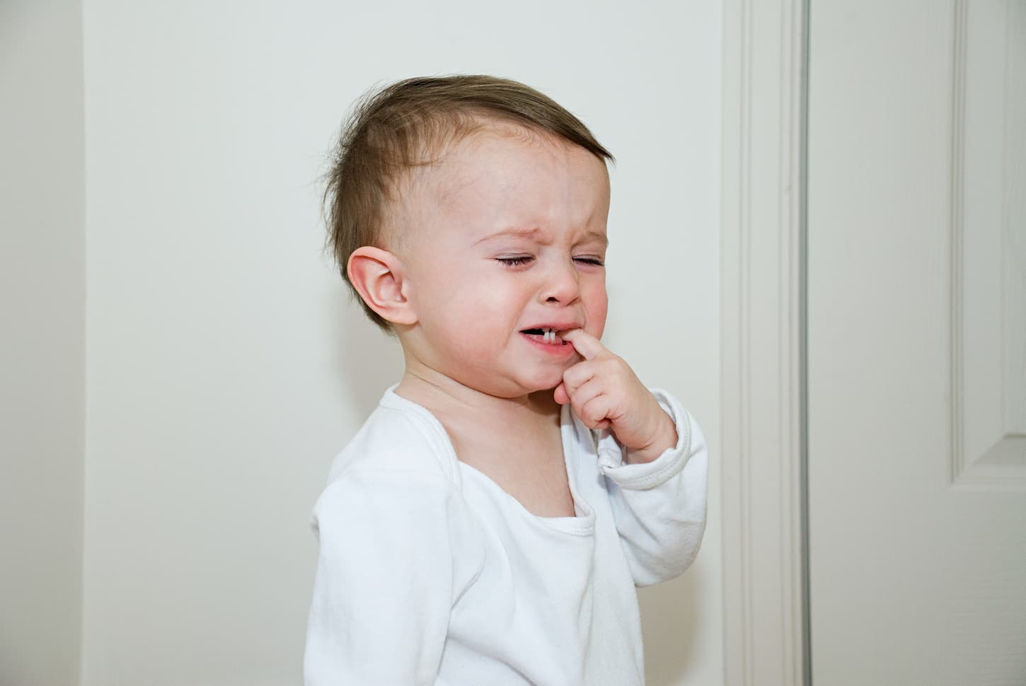 An image of a baby boy teething and looking uncomfortable.