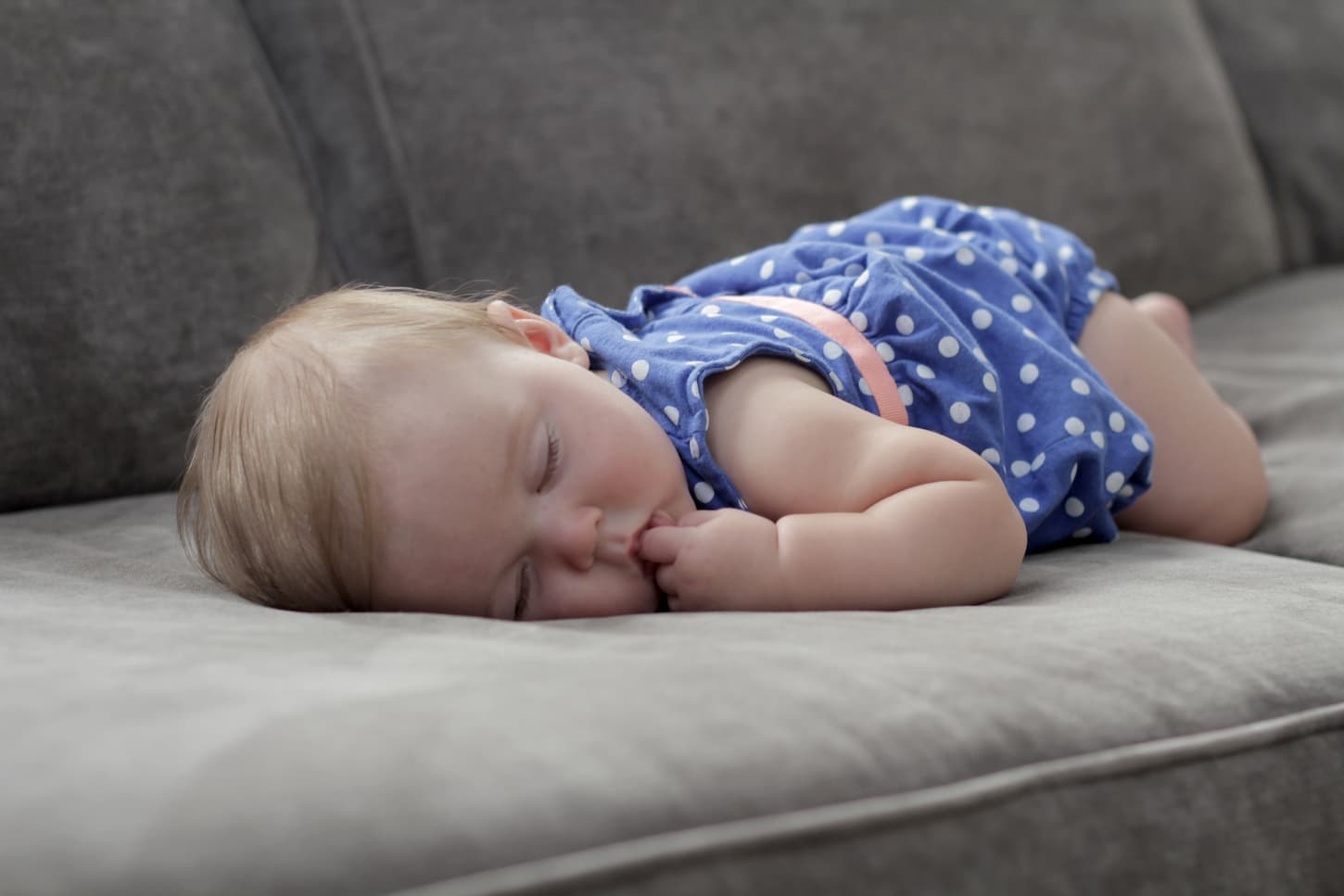 An image of a sleeping baby on a couch aging about 4 months old