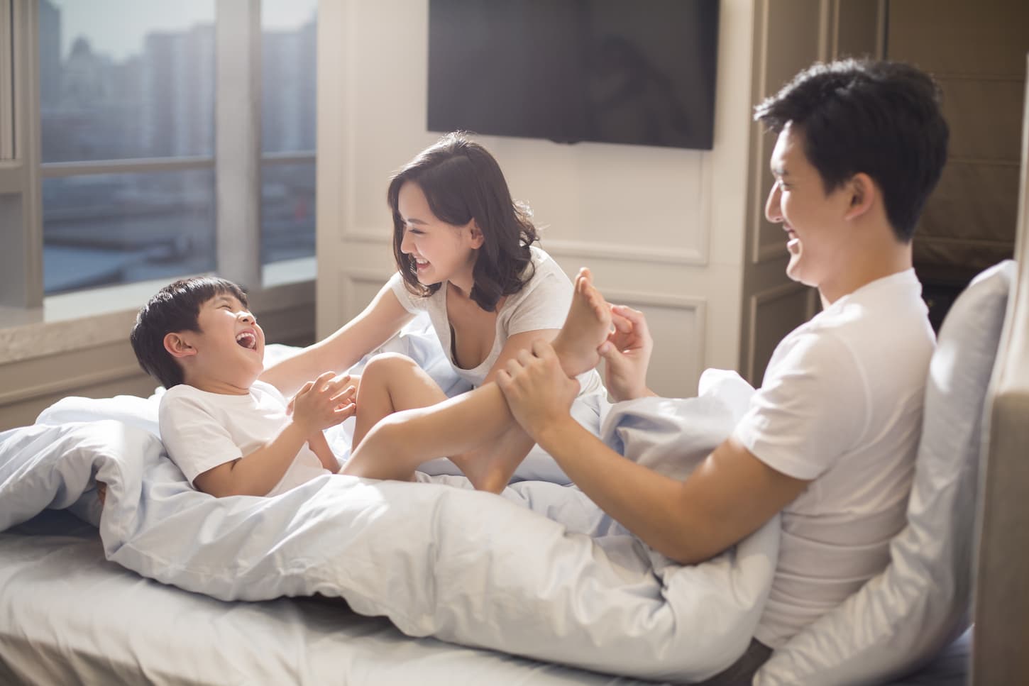 An image of a Cheerful young family having fun on a bed.