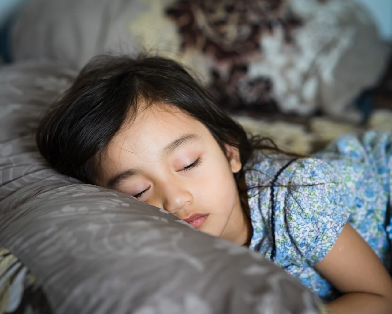An image of a Daytime sleeping time of a toddler child on the bed.